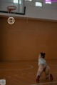 A woman kneeling on a basketball court with a basketball hoop.