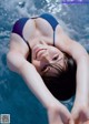 A woman in a blue bikini laying in a pool.